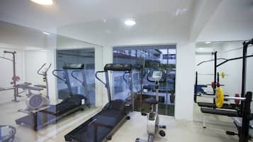 Uma academia com esteira ergométrica, elíptico e aparelhos de musculação.