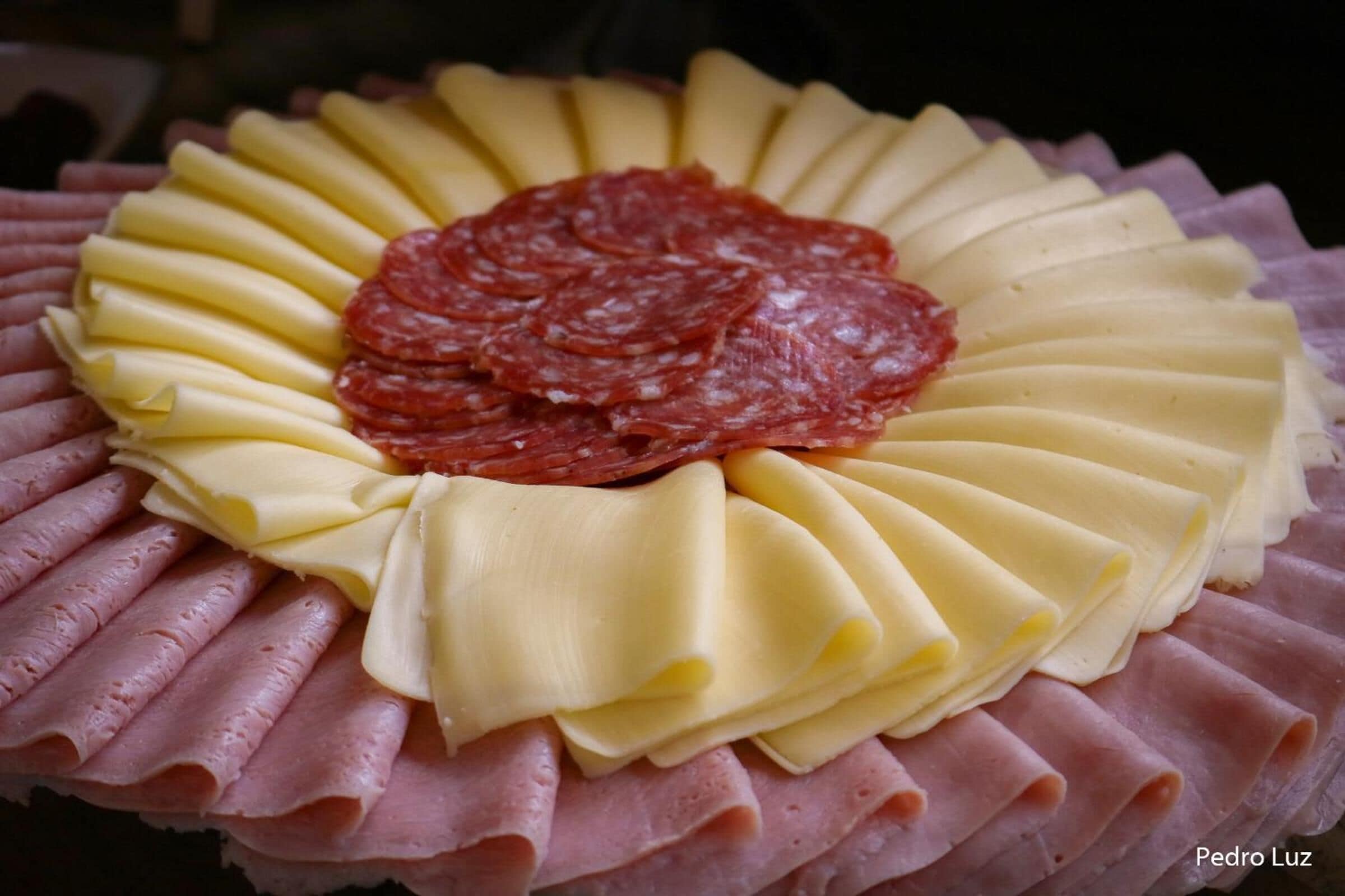 A platter of sliced meats and cheese arranged in a circular pattern.