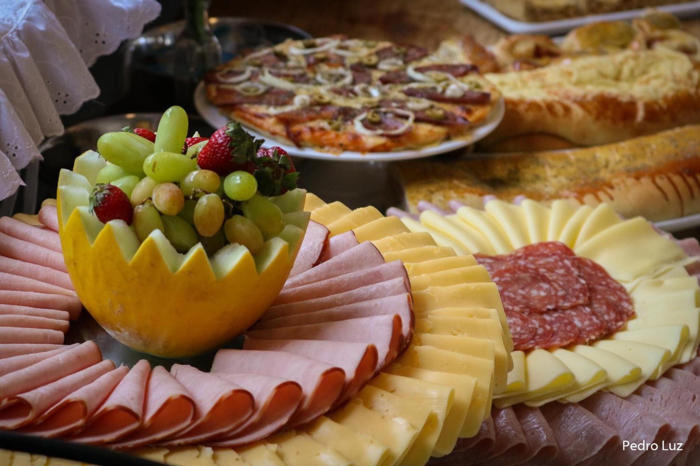 Tábua de frios com diversos queijos, embutidos e frutas.