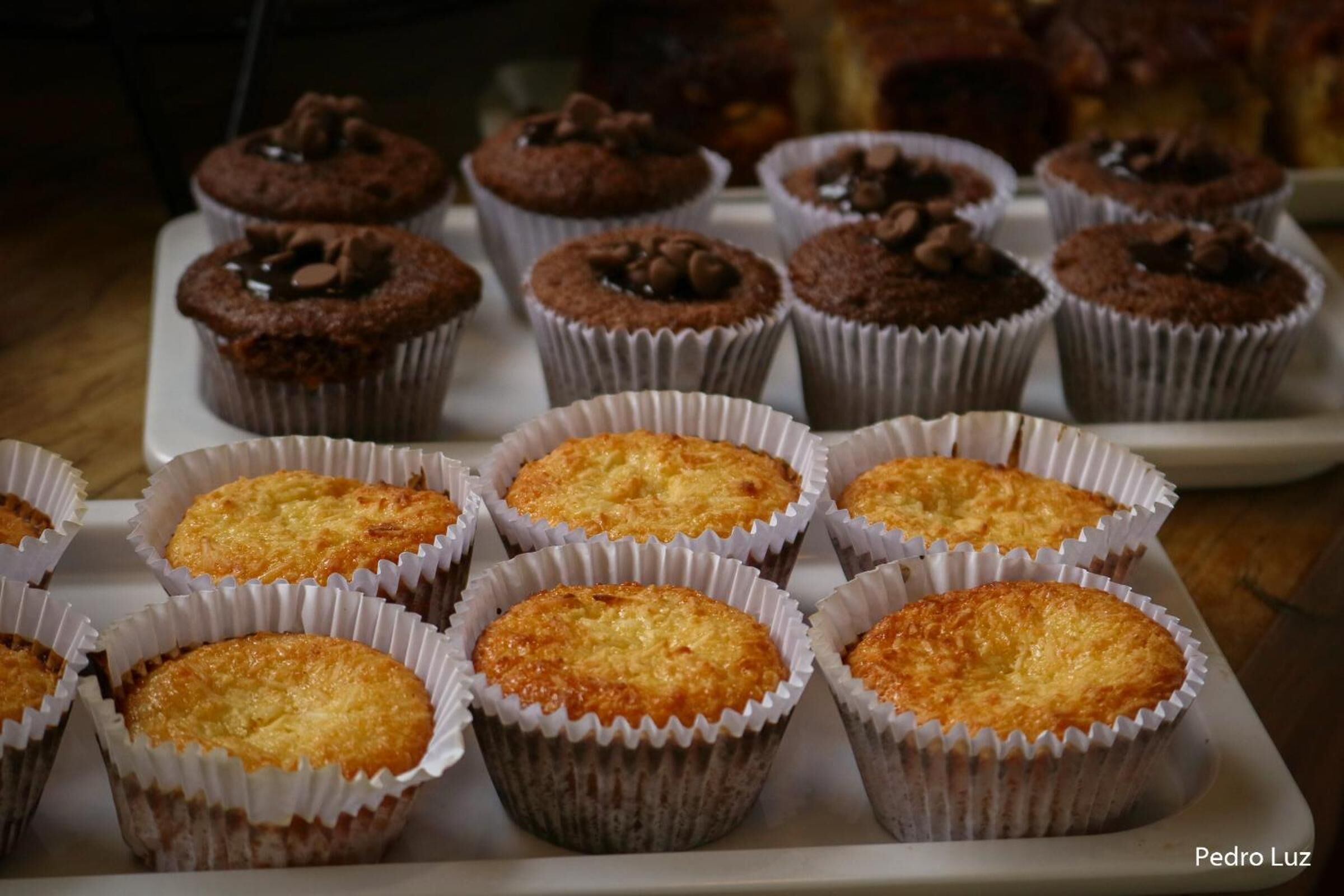 Una bandeja de muffins en vasos de papel, algunos cubiertos de chispas de chocolate.