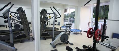 Un gimnasio con diversos equipos de ejercicio, incluyendo cintas de correr, un banco de pesas y una estructura para sentadillas.