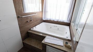 Uma casa de banho moderna com banheira, chuveiro, toucador com espelho e janela com cortinas.