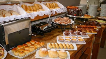 Un bufé con diversas opciones de panadería, incluyendo pan, muffins y pasteles.