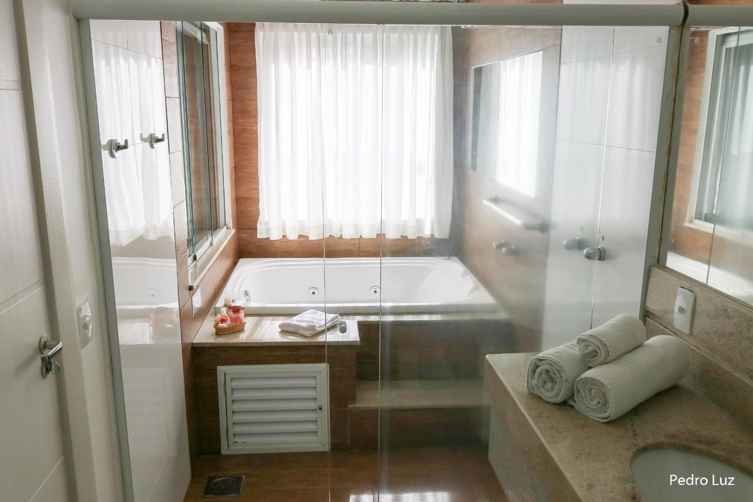 Un baño moderno con cabina de ducha de vidrio, bañera y tocador con perchero.