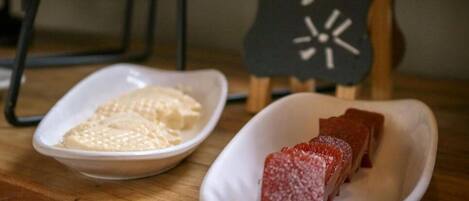 A table with two white dishes, one containing a white food item and the other a red food item, with a sign reading "Bom Dia!" in the background.