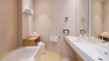 Une salle de bain moderne avec une baignoire, deux lavabos, un meuble-lavabo en bois et un grand miroir.