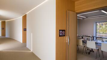 A modern hotel lobby with a curved wall, a reception desk, and a conference room with tables and chairs.