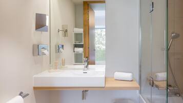 Une salle de bain moderne avec un grand miroir, un lavabo et une douche à parois de verre.