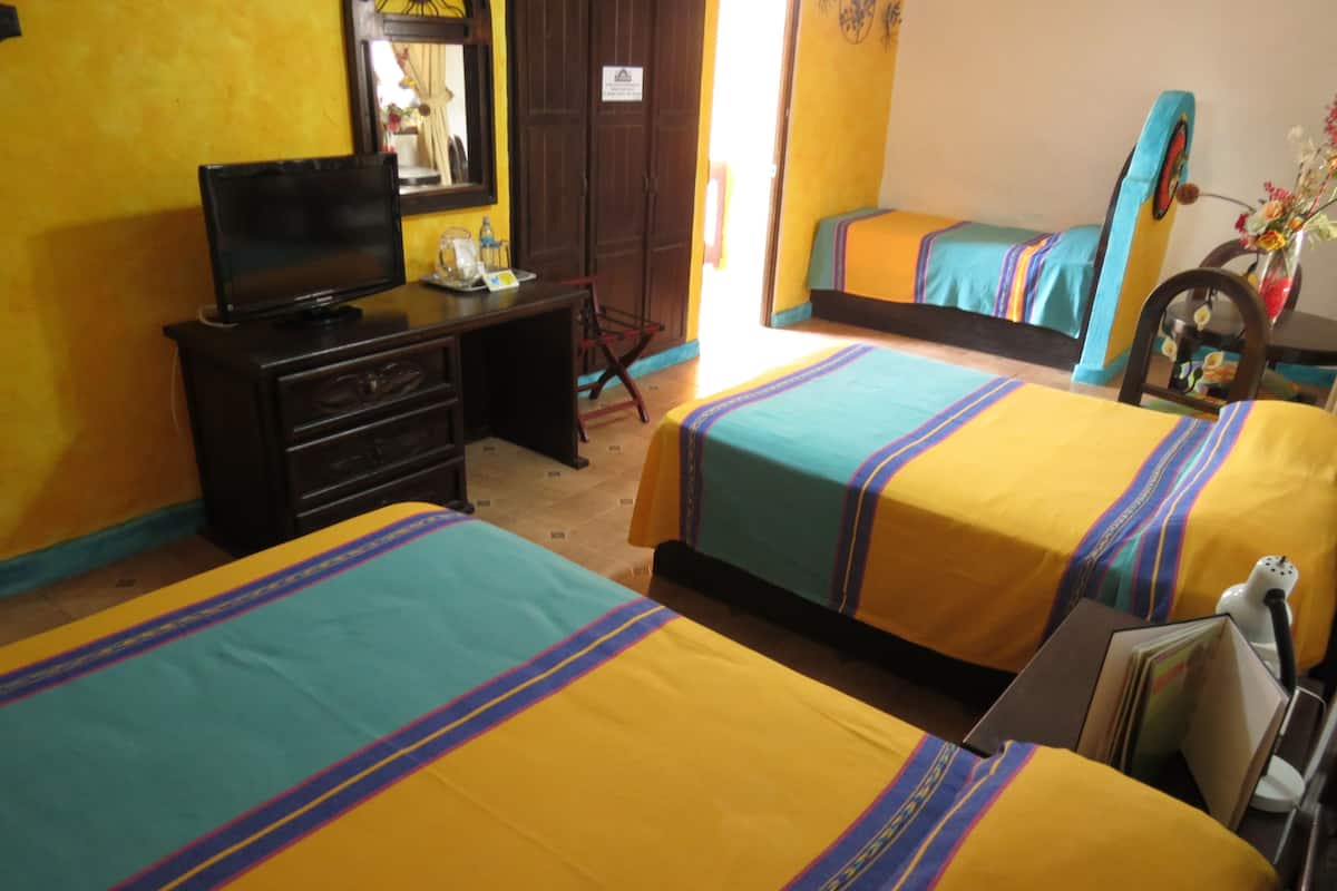 A hotel room with two beds, a desk with a television, a dresser, and a mirror.