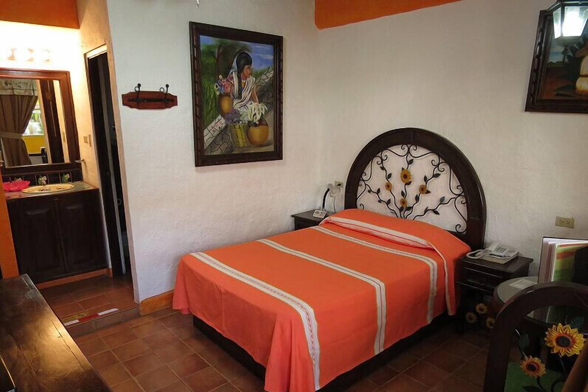 A bedroom with a bed, a nightstand, a dresser, and a painting on the wall.