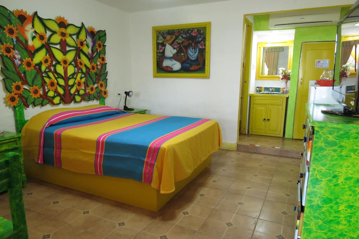 A room with a bed, a painting, a sink, and a mirror.