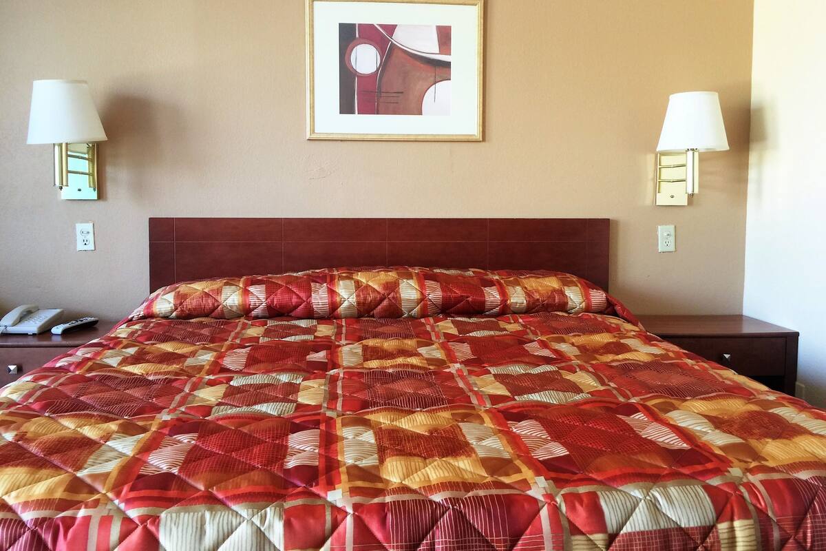 A hotel room with a large bed, two bedside lamps, a framed picture on the wall, and a phone on the nightstand.