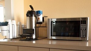 A kitchenette with a coffee maker, microwave, and cabinets. - Bama Inn (Huntsville)