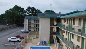 A hotel with a swimming pool, outdoor seating, and a parking lot. - Bama Inn (Huntsville)