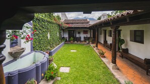 A courtyard with a tiled roof, potted plants, and a small garden area. - Hotel Casa Naranjo (Antigua Guatemala)