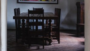 A dining area with a table and chairs, a chandelier, and a framed floral painting on the wall. - Hotel Casa Naranjo (Antigua Guatemala)