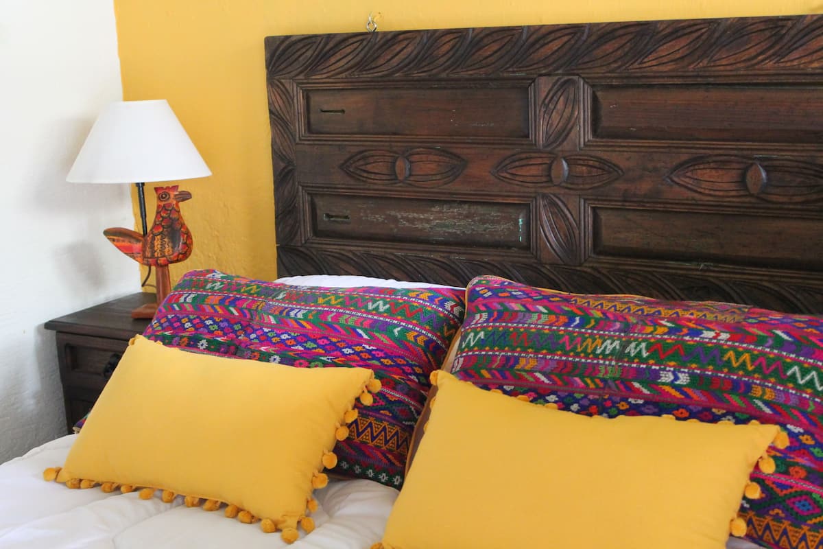 Una cama con almohadas de colores y un cabecero de madera.