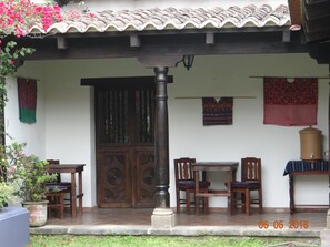 A traditional house with a tiled roof, wooden doors, and a porch area with chairs and a table. - Hotel Casa Naranjo (Antigua Guatemala)