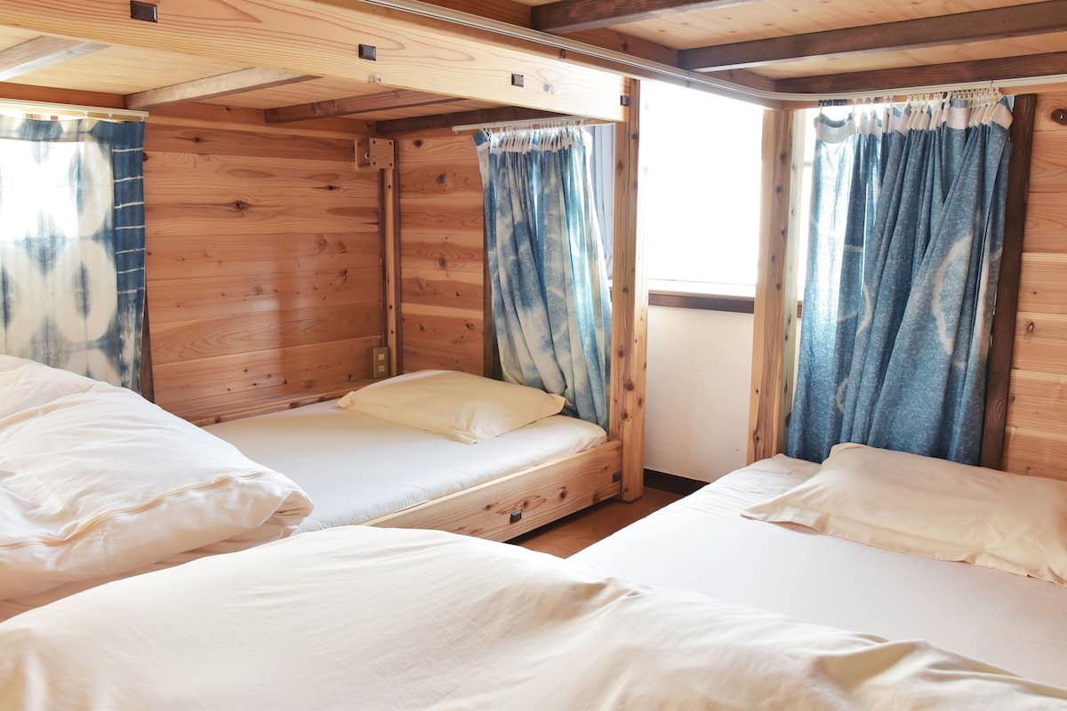 Una cabaña con dos camas de madera, cada una con ropa blanca de cama y una sola almohada.