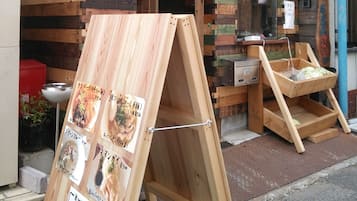 A small wooden structure with a sloped roof, a signboard, and a display stand with menus.