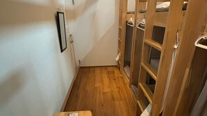 Un pasillo estrecho con suelo de madera, un banco con contenedores de almacenamiento y una escalera de madera que ofrece vistas al piso superior.