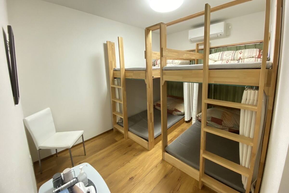 A bunk bed room with a white chair and a small table with toiletries.
