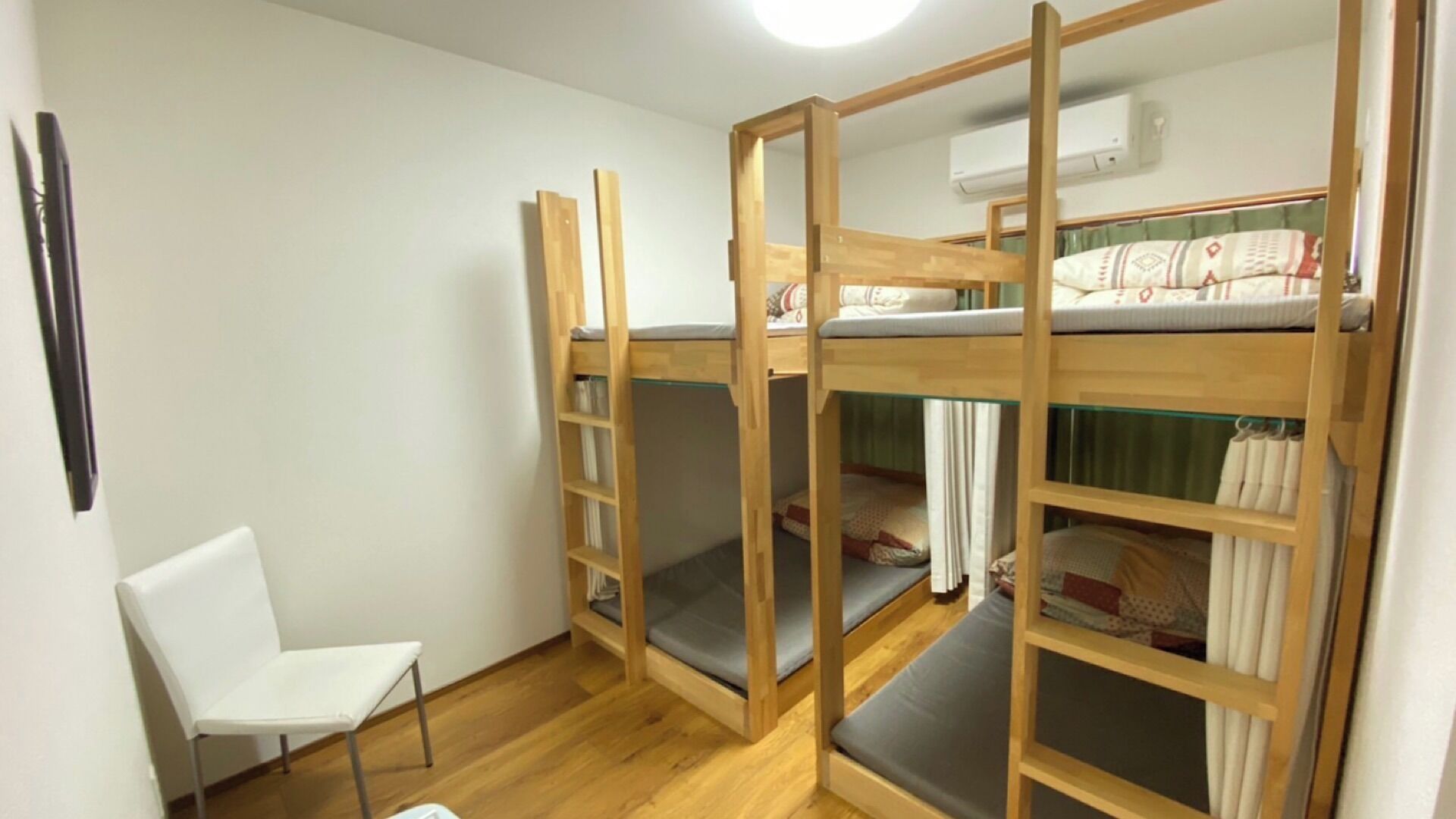 Une chambre avec un lit superposé, une chaise, des murs en bois et un appareil de climatisation.