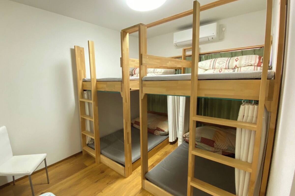 A bunk bed room with a chair, wooden walls, and an air conditioning unit.