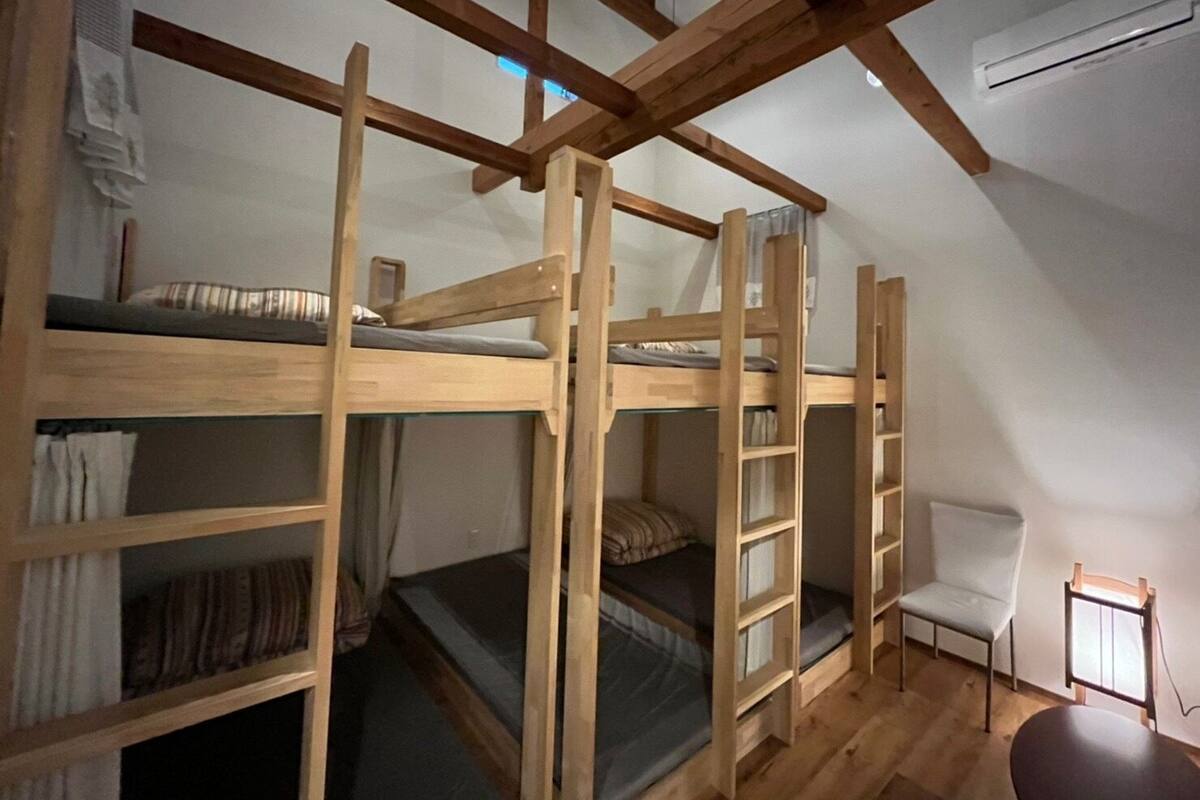 A dormitory room with bunk beds, a chair, and a small table.