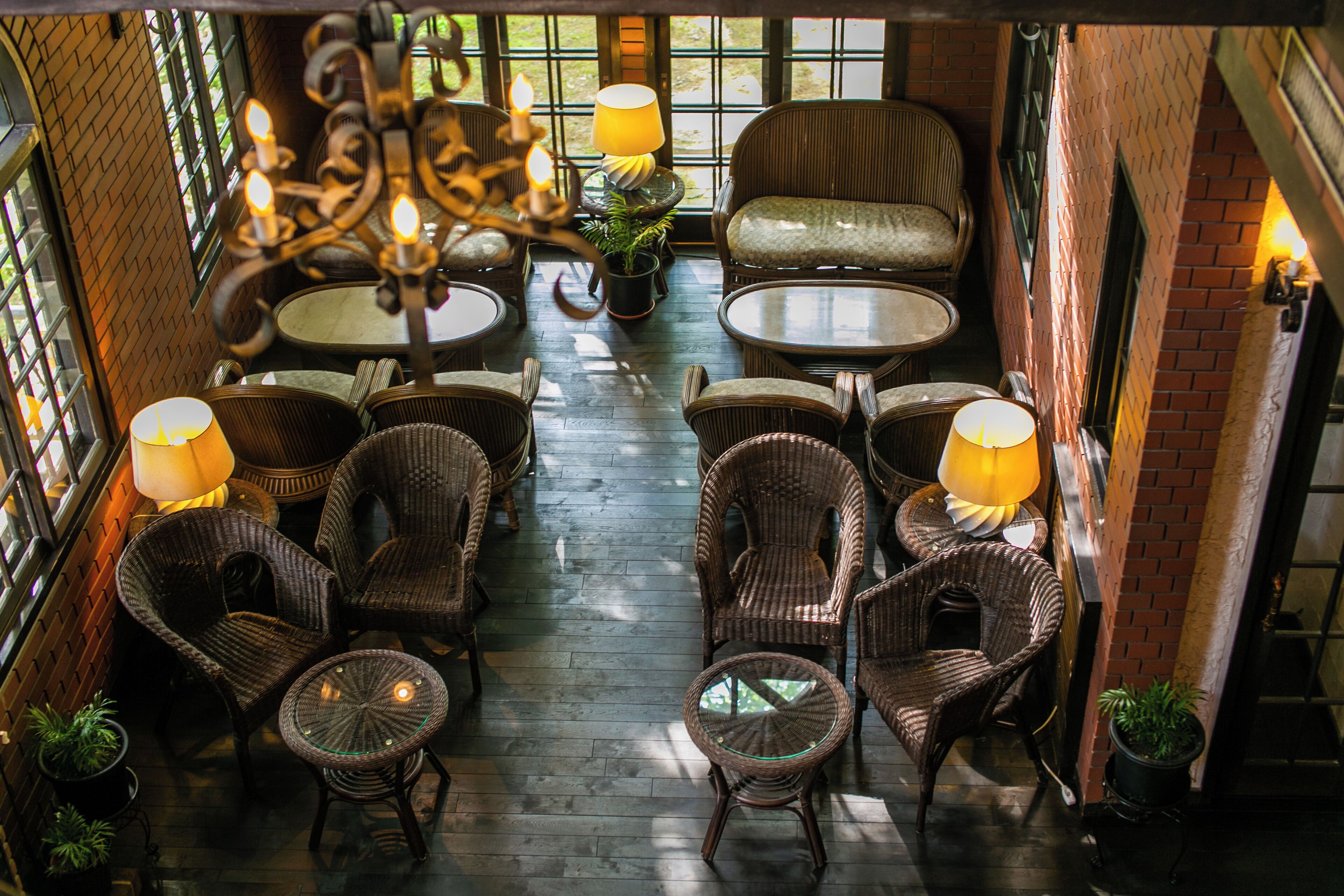 A cozy indoor seating area with wicker furniture, round tables, and ambient lighting.