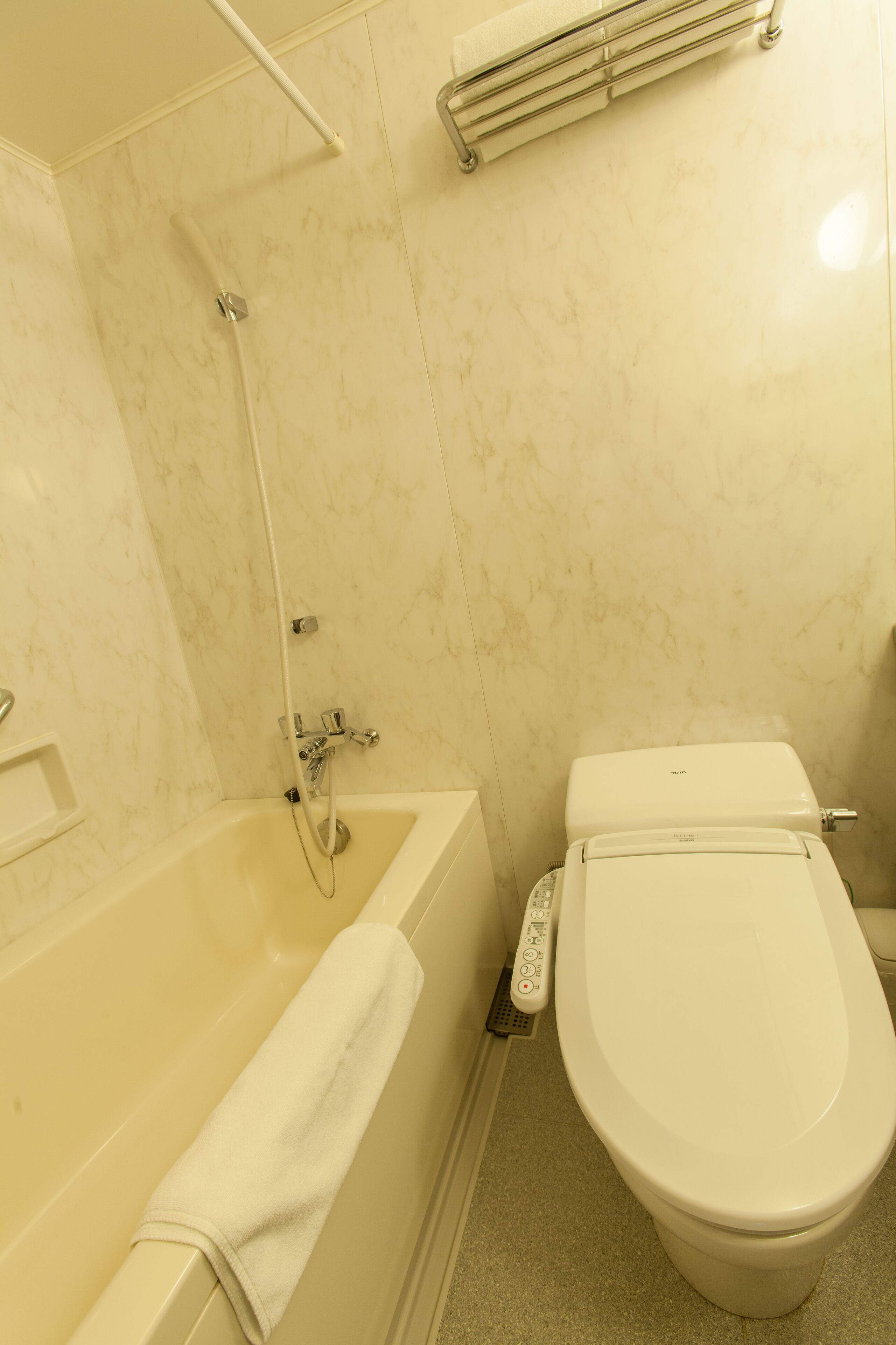 A bathroom with a bathtub, toilet, and a control panel on the wall.