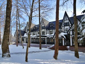 A large, multi-story building with a symmetrical facade, featuring a mix of rectangular and arched windows, and a steeply pitched roof. - Restaurant & Hotel Traumerei (Hakuba)