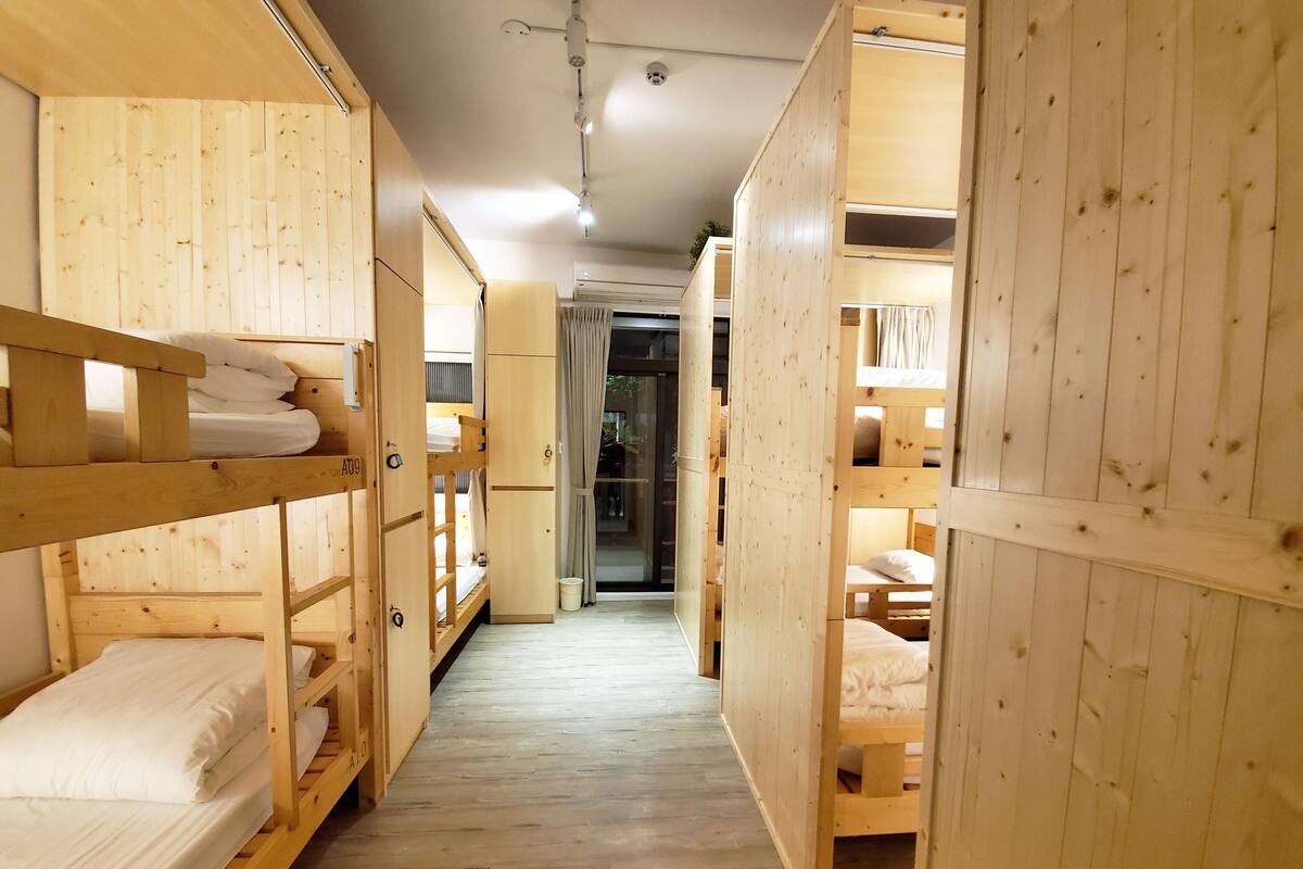 A corridor with wooden bunk beds, a visible air conditioning unit, and a door leading to another room.