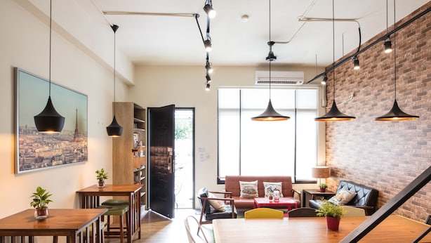 A modern dining area with wooden tables and chairs, a staircase, and a brick wall. - On My Way Taitung Hostel Backpacker (Taitung)