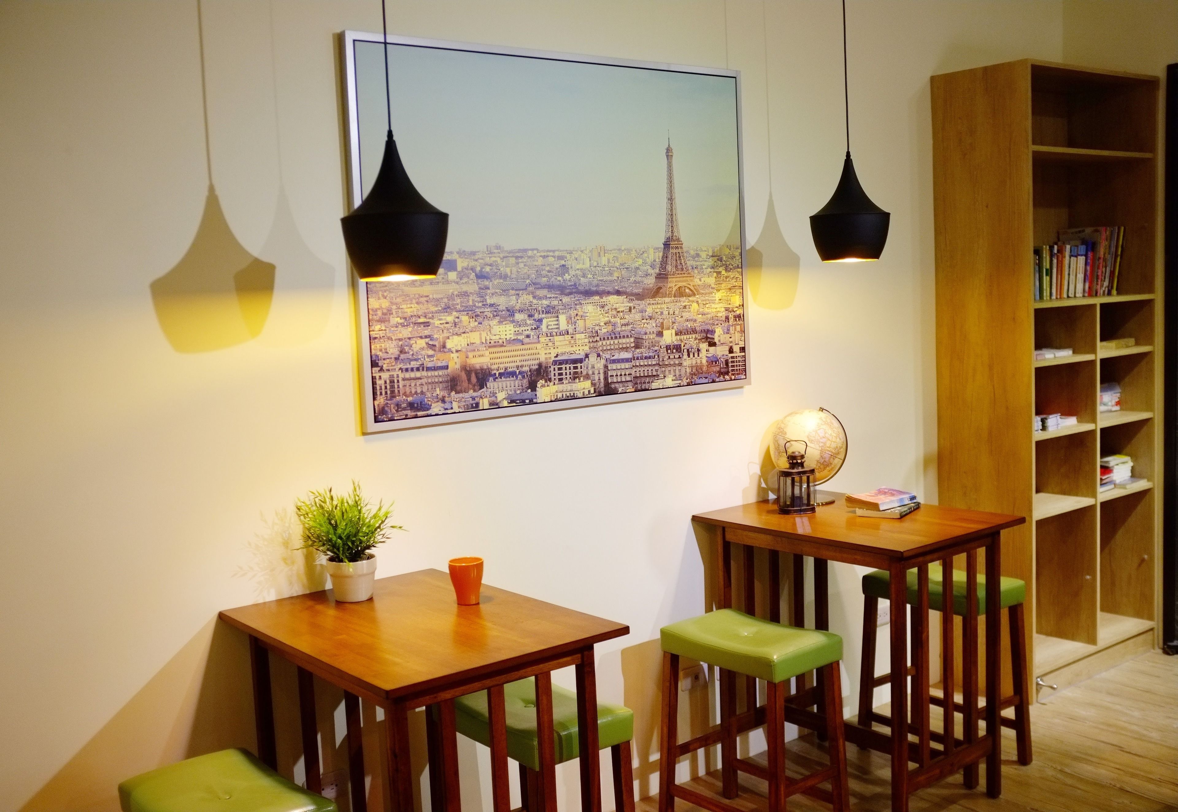 Una habitación acogedora con una mesa de madera, taburetes verdes, un globo terráqueo y una estantería.