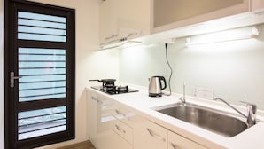 A kitchen with a sink, stove, and window with blinds. - On My Way Taitung Hostel Backpacker (Taitung)
