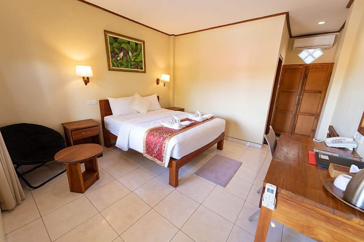 A hotel room with a bed, bedside tables, a desk with a telephone, and a small seating area.