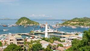 A coastal marina with boats, a lighthouse, and a pier. - Komodo Lodge (Labuan Bajo)