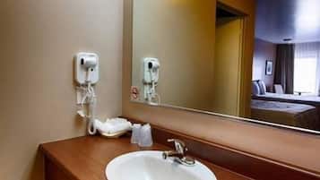 A hotel bathroom with a wooden vanity, a white sink, a mirror, and a hairdryer.