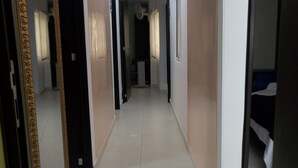 Un pasillo con tragaluces, una puerta con el número y un espejo que refleja parte del cuarto.