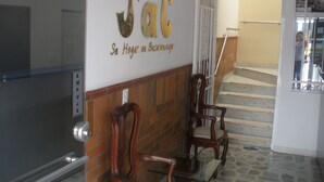 Un área de recepción con un letrero que dice "CASA Jac" y una escalera que sube a un piso superior.