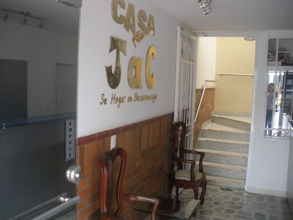 A reception area with a sign reading "CASA Jac" and a staircase leading to an upper floor.