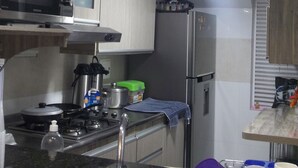 Una cocina compacta equipada con microondas, estufa y refrigerador.