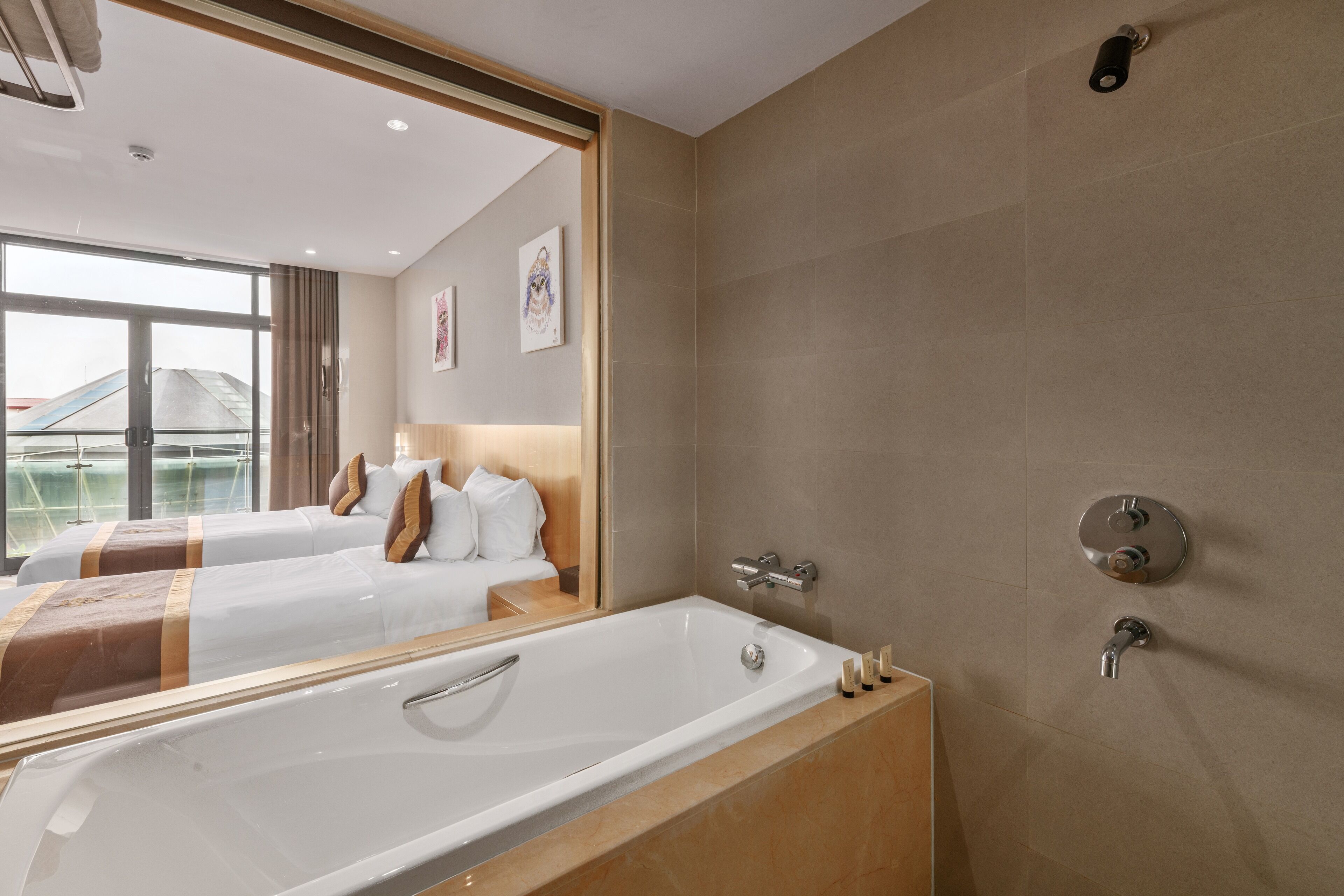 A hotel room with a large bathtub, two beds with headboards, a large mirror, and a view of a building outside.