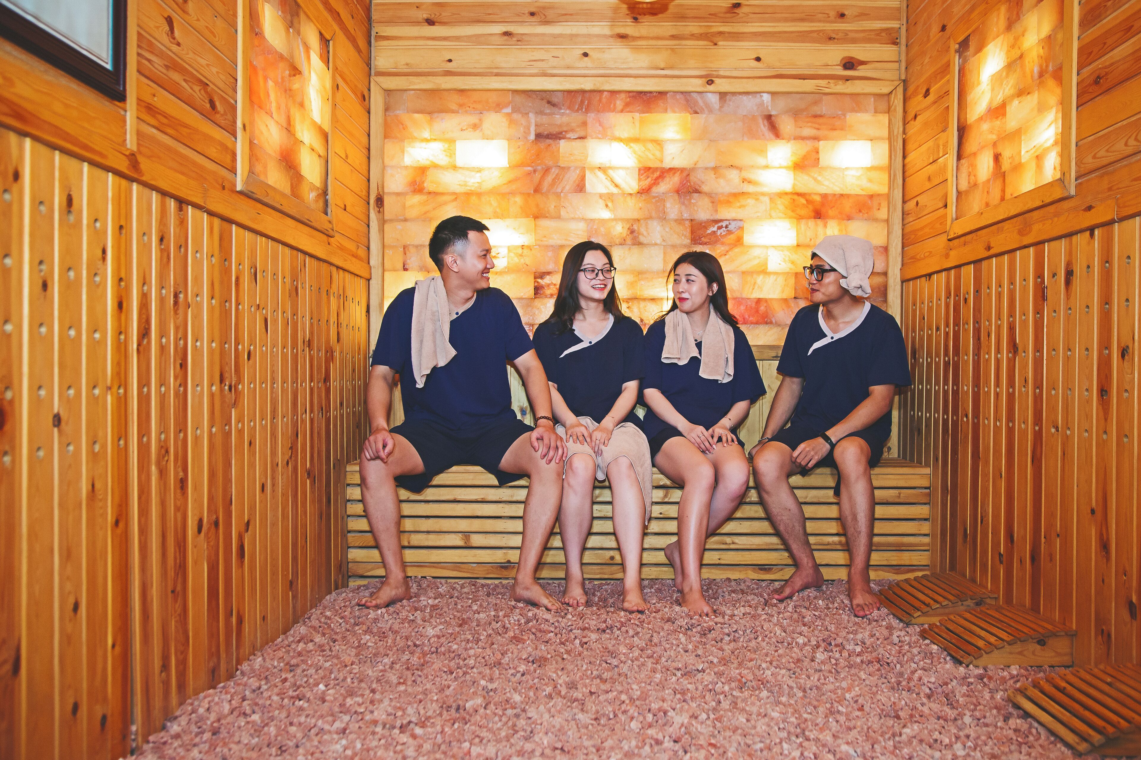 A wooden sauna with benches, a pebble floor, and a wall with embedded lights.