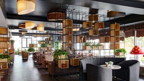 A modern interior with a central seating area, wooden shelving units, and potted plants. - The Reed Hotel (Ninh Binh)
