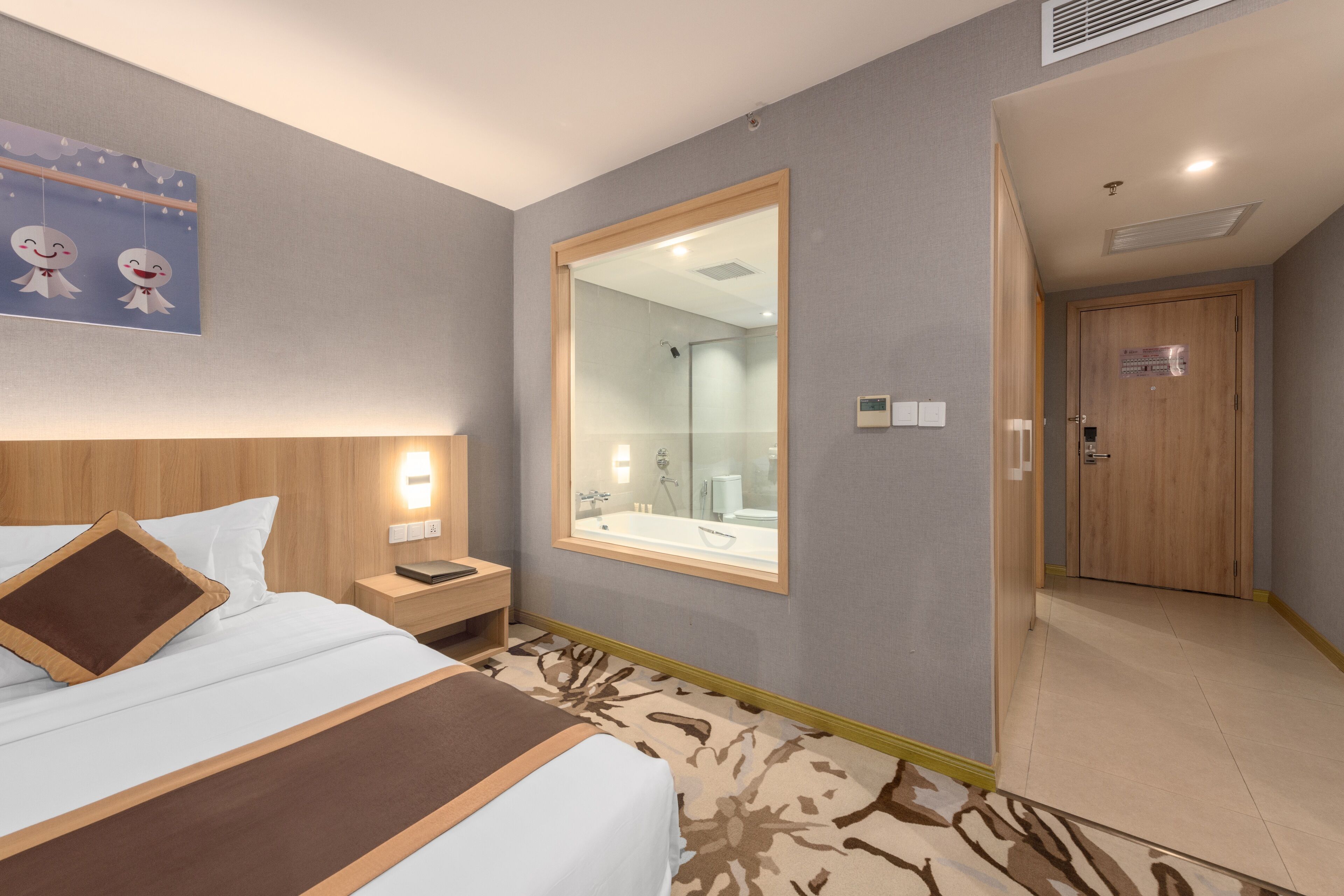 A hotel room with a bed, bedside table, nightstand, and a large mirror.