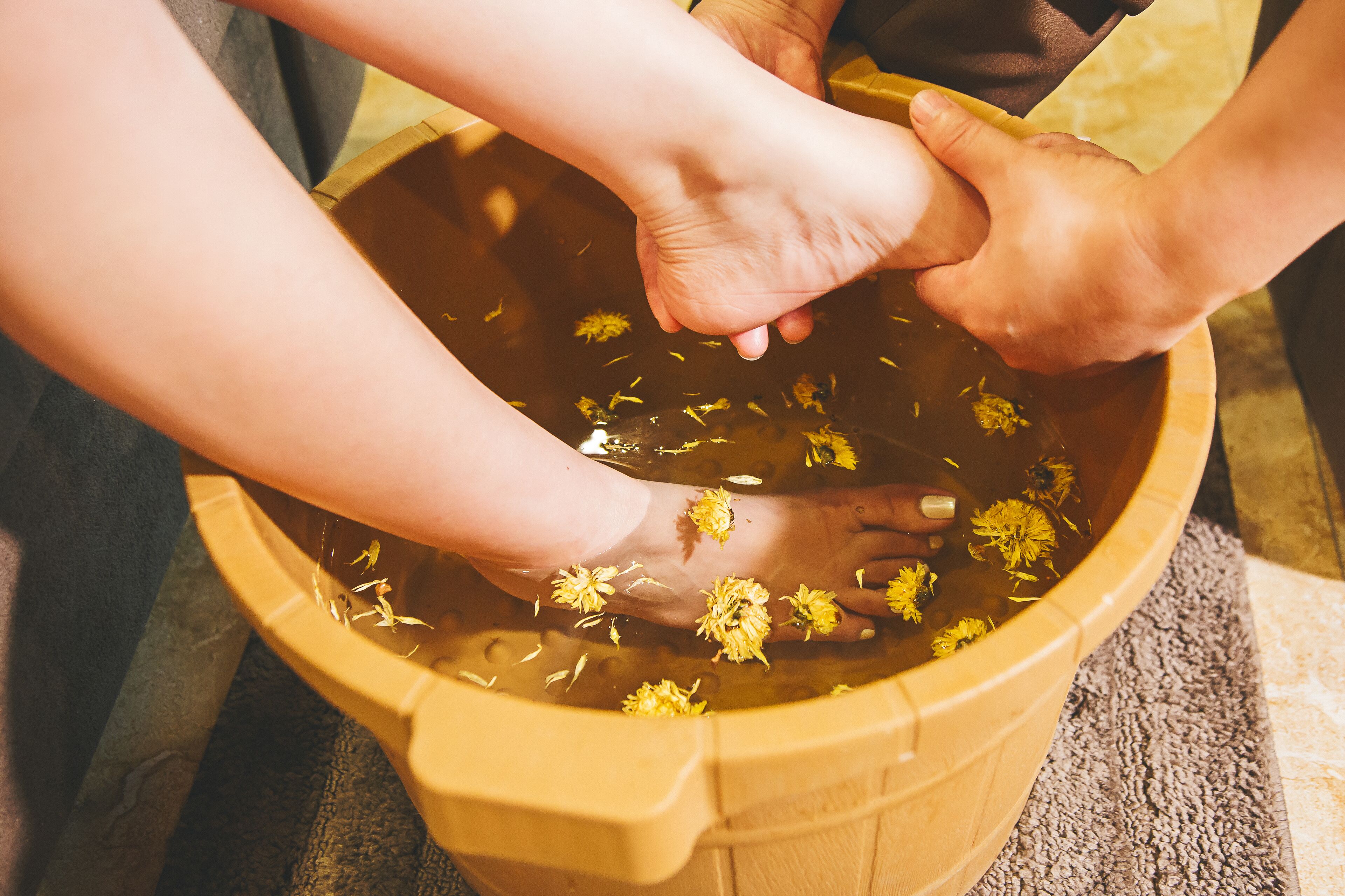 A wooden tub filled with water and flowers, with hands reaching into it.