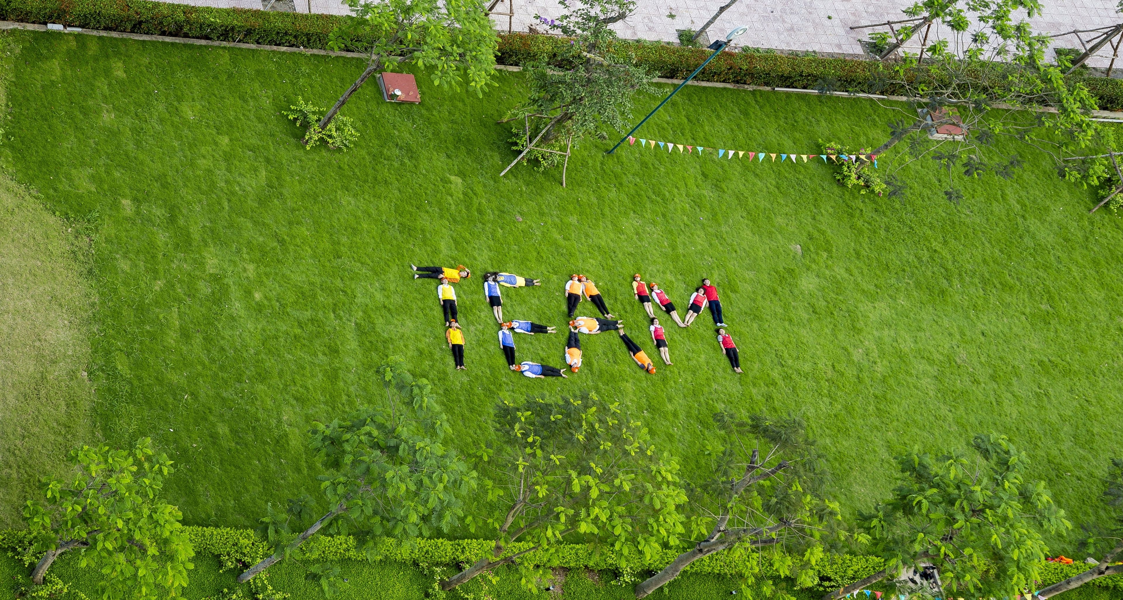 A group of people arranged in a heart shape on a grassy field.