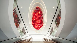 A modern interior with a central red sculpture, glass railings, and a staircase. - The Reed Hotel (Ninh Binh)